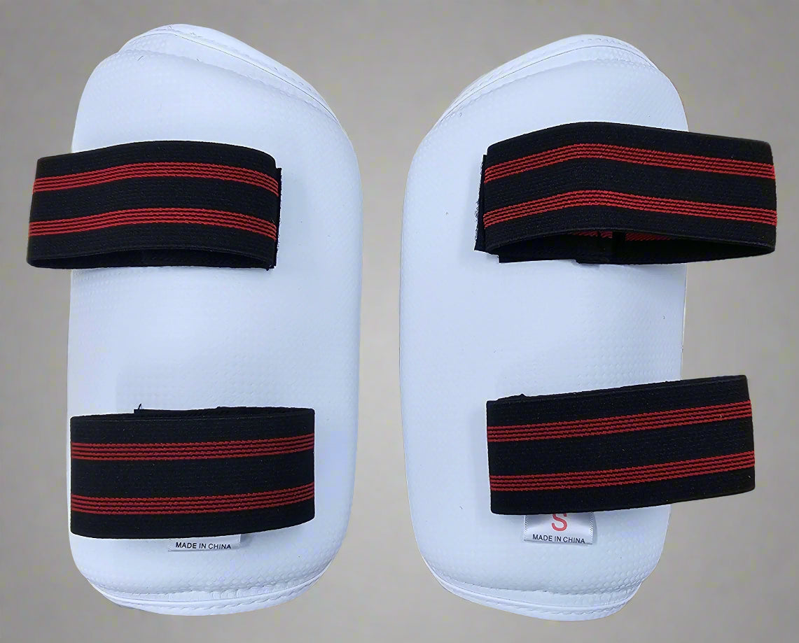 Pair of white forearm protective pads with black and red straps 